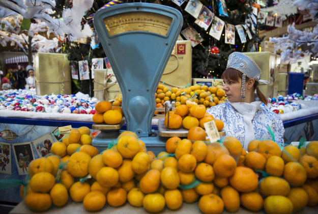 A seller dressed as a Snow Maiden, waits for customers to buy tangerines, traditional fruit for the New Year in Russia, at GUM Department Store in Red Square in Moscow, Russia.