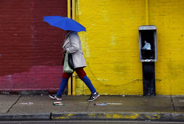 A woman walks in the rain on Hamilton Avenue, Tuesday, Dec. 29, 2015, in Passaic, N.J. 