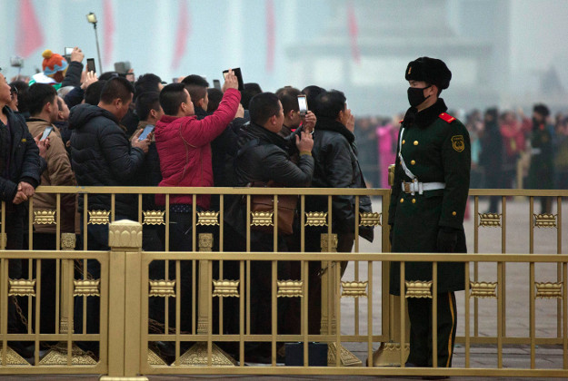 A Chinese military policeman wears a mask to protect against the pollution during the daily flag lowering ceremony on Tiananmen Square in Beijing, China. Image by AP Photo/Ng Han Guan.