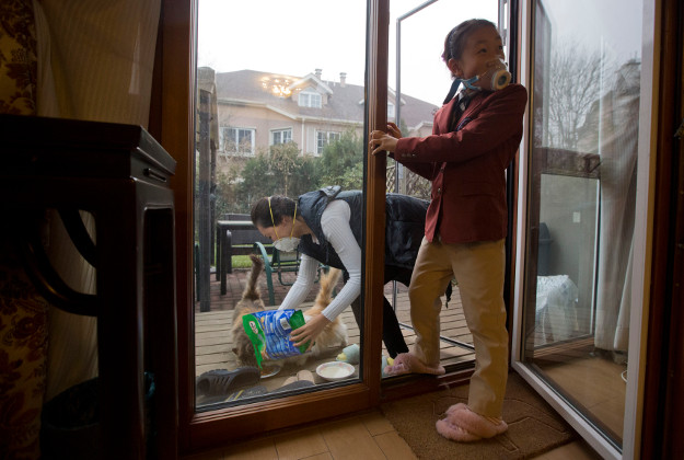 Eight-year-old Zhao Hanxiao and her mother Han Xiao demonstrate how they would wear masks even when they venture outside to feed stray cats at their home in Beijing, China. Image byAP Photo/Ng Han Guan.