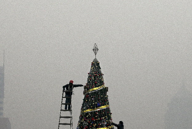 Workers install a Christmas tree on display outside a shopping mall during a heavily polluted day in Beijing. 