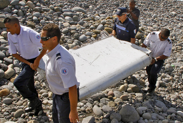 In this July 29, 2015 file photo, French police officers carry a piece of debris from a plane in Saint-Andre, Reunion Island. The wing was later found to be from missing Malaysia Airlines Flight 370 that went missing March 8, 2014, with 239 people aboard while flying from Kuala Lumpur to Beijing.