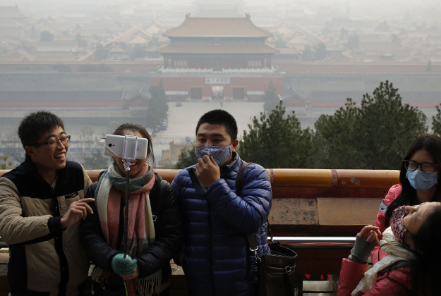 isitors, some wearing masks to protect themselves from pollutants, share a light moment as they take a selfie at the Jingshan Park on a polluted day in Beijing, Monday, Dec. 7, 2015. 