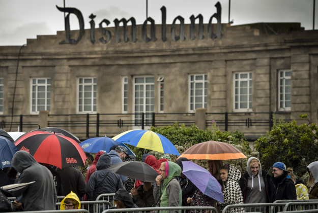 People queue in the rain to buy tickets for Banksy's exhibition theme park 'Dismaland' at Weston-super-Mare, Somerset. 